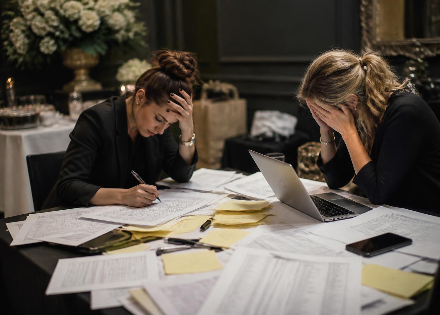 Event organisers working through printed guest lists and notes before an event